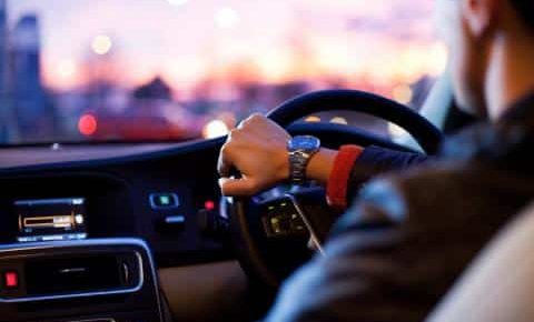 A man wearing a watch, driving his car